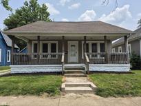 Charming single-story home featuring a cozy front porch with wood railings and a well-maintained lawn at 1033 Cottage Ave, Columbus, IN 47201