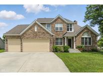Charming brick two-story home with a three-car garage and well-manicured lawn and shrubbery at 10410 Trillium Ct, Noblesville, IN 46060