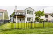 Beautiful backyard featuring an iron fence, lush green grass, a cozy deck, and mature trees at 13091 Duval Dr, Fishers, IN 46037