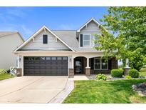 Charming two-story home with a well-manicured lawn, dark garage, and welcoming front porch at 1412 Huntzinger Blvd, Pendleton, IN 46064