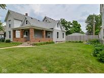 Charming two-story home with inviting front porch and lush green lawn at 305 N Warman Ave, Indianapolis, IN 46222