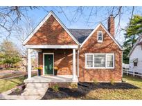 Charming brick home featuring a cozy front porch, green door, and manicured landscaping at 6640 E Washington St, Indianapolis, IN 46219