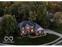 Aerial view of a brick two-story home with a well-manicured lawn and mature trees at 9703 Fortune Dr, Fishers, IN 46037