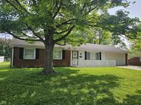 Charming brick ranch-style home featuring a well-manicured lawn and mature shade tree in front yard at 2017 Schwier Ct, Indianapolis, IN 46229
