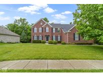 Traditional brick home with a well-manicured lawn and mature trees showcases classic American architecture at 11036 Ravenna Way, Indianapolis, IN 46236