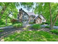 Stunning stone-and-brick home with lush landscaping, mature trees, and circular driveway at 12380 Creekwood Ln, Carmel, IN 46032