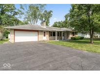Charming single-story home with stone facade, attached garage, mature trees, and spacious front yard at 1613 Park Rd, Anderson, IN 46011