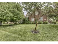 Beautiful two-story brick home featuring a manicured lawn, mature trees, and charming architectural details at 2553 Forest Hills Blvd, Greenwood, IN 46143