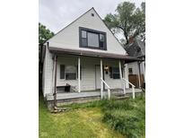 Exterior front view of a two-story home with a small porch and overgrown landscaping at 319 S Temple Ave, Indianapolis, IN 46201