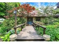 Charming front entrance features a wooden bridge walkway surrounded by lush landscaping at 3317 S 100 E, Greenfield, IN 46140