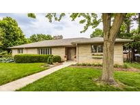 Charming ranch-style home with a stone facade, manicured lawn, and mature trees at 4415 N Illinois St, Indianapolis, IN 46208