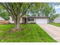 Charming single-story home featuring an attached garage, mature trees, and a well-maintained lawn at 6310 Kellum Dr, Indianapolis, IN 46221