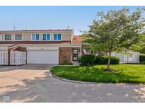 Charming brick townhome featuring an attached garage, manicured lawn, and mature landscaping at 1510 Dominion Dr, Zionsville, IN 46077