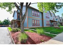 Charming townhouse with a colorful exterior, landscaped front yard, and inviting front porch at 1635 N College Ave # 4, Indianapolis, IN 46202