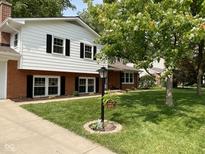 Charming home featuring brick and white siding, manicured lawn, and black window shutters at 3520 Lantern Ln, Columbus, IN 47203