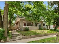 Charming home with a front porch, landscaped yard, and mature trees at 4048 N College Ave, Indianapolis, IN 46205