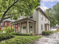 Charming two-story home with a covered front porch, American flag, and professionally landscaped yard at 4455 Central Ave, Indianapolis, IN 46205