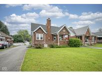 Charming brick home featuring a well-manicured lawn, inviting front porch, and classic architectural details at 5435 E 10Th St, Indianapolis, IN 46219
