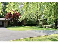 Charming single-story brick home with a well-manicured lawn, mature trees, and circular driveway at 6519 Creekside Ln, Indianapolis, IN 46220