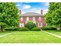 Charming two-story brick home with mature trees and a lush green lawn under a blue sky at 8436 E 56Th St, Indianapolis, IN 46216