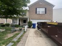 Two-story home featuring a brick facade, attached garage, well-kept lawn and trash dumpsters in driveway at 12509 Teacup Way, Indianapolis, IN 46235