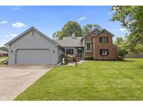 Charming home with two-car garage, lush lawn and beautiful landscaping with bright flowers at 13153 Tudor Dr, Carmel, IN 46033