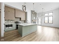 A modern, open-concept kitchen features stainless steel appliances and a large island with quartz countertops at 1677 Solebar Way, Westfield, IN 46074