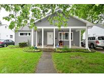 Charming home with a covered front porch, well-maintained lawn, and mature trees offering shade at 4751 N Longworth Ave, Indianapolis, IN 46226