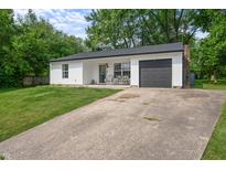 Charming single-story home featuring white siding, a gray garage door, and a well-manicured front lawn at 5811 Simmul Cir, Indianapolis, IN 46221