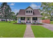 Charming home featuring a lush lawn, landscaped flower beds, and a welcoming front porch with rocking chairs at 616 S Fuller Dr, Indianapolis, IN 46241