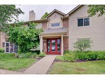 Inviting exterior of a two-story home with a brick facade and red double-door entry framed by mature landscaping at 1074 Timber Creek Dr # 8, Carmel, IN 46032