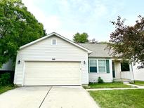 Charming single-story home featuring a two-car garage, manicured lawn, and lush surrounding trees at 10922 Snowdrop Way, Indianapolis, IN 46235