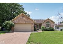 Charming brick home with well-manicured lawn and a two-car garage on a sunny day at 1311 Old Hickory Dr, Greenwood, IN 46142