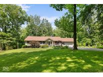 Charming single-story home with a manicured front yard, mature trees, and an attached garage, all bathed in sunlight at 1350 Inverness Farms Rd, Martinsville, IN 46151