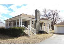 Charming single-story home with stone chimney and inviting covered porch, and a detached garage at 1739 Forest Dr, Indianapolis, IN 46227