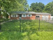 Charming brick ranch-style home featuring a black fence and inviting curb appeal with lush greenery at 2180 N Irwin St, Indianapolis, IN 46219