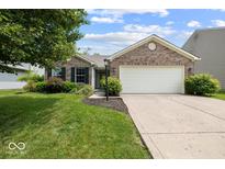 Charming single-story brick home featuring an attached two car garage, a manicured lawn and mature trees at 5967 Peregrine Blvd, Indianapolis, IN 46228