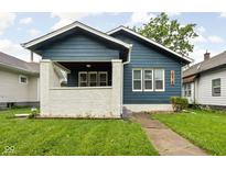 Charming blue home featuring a quaint front porch, lush lawn, and inviting curb appeal at 614 N Drexel Ave, Indianapolis, IN 46201