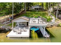 Inviting boat dock with lounge area, bar-height table, and covered boat slip, ideal for lakeside enjoyment at 6492 Osprey Dr, Nineveh, IN 46164