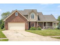 Charming two-story brick home with a covered porch, beautiful lawn, and manicured garden at 7082 Hunters Ridge Dr, Plainfield, IN 46168