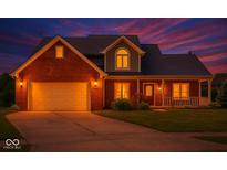 Beautiful two-story brick home with a front porch and manicured lawn at dusk at 7082 Hunters Ridge Dr, Plainfield, IN 46168