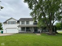 Charming two-story home with front porch, attached garage, and a large tree in a lush, green lawn at 7195 W 700 N, Fairland, IN 46126