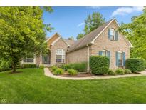 Charming brick home with manicured lawn, complemented by lush landscaping and blue shutters at 7818 Fawnwood Dr, Indianapolis, IN 46278