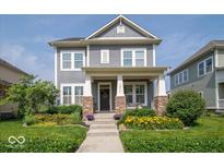 Charming two-story home with a beautifully landscaped front yard and inviting covered porch with stone accents at 12976 Walbeck Dr, Fishers, IN 46037
