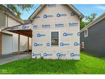 Exterior view of home featuring protective builder's wrap, a window, and a tidy lawn at 1917 Union St, Indianapolis, IN 46225