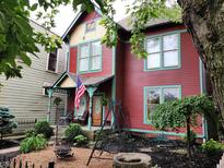 Charming red two-story home featuring a quaint front porch and mature landscaping at 239 E 11Th St, Indianapolis, IN 46202