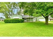Charming single-story home with green exterior, a well-manicured lawn, and mature shade trees at 415 N 3Rd St, Elwood, IN 46036
