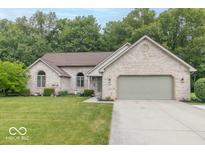 Charming brick home featuring a two-car garage, well-maintained lawn, and beautiful landscaping at 5104 W Prairiewood Dr, Muncie, IN 47304