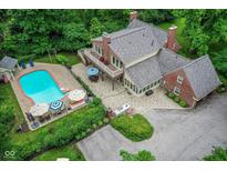 Stunning aerial view of a brick home with a pool, patio, and lush greenery at 6220 E 56Th St, Indianapolis, IN 46226