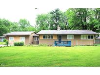 Charming single-story home with a well-manicured lawn and a cozy blue front porch at 6601 Twin Brooks Dr, Indianapolis, IN 46227